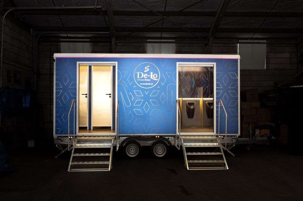 Korte nachtelijke foto van de DL DELUXE toiletwagen met twee verlichte ingangen